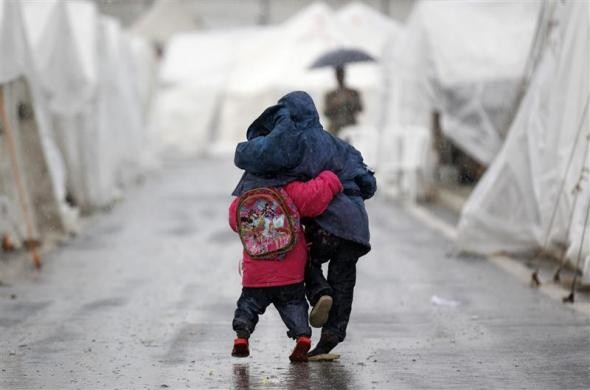 Một cậu bé Syria che mưa cho em trai nhỏ tại trại tị nạn Boynuyogun, Hatay, Thổ Nhĩ Kỳ ngày 8/2/2012.