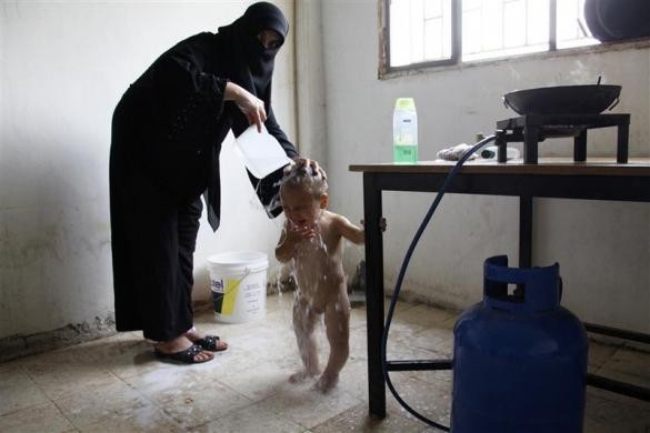 Một phụ nữ Syria tắm rửa cho cậu con trai nhỏ trong nhà bếp bỏ hoang tại Wadi Khaled, miền bắc Lebanon ngày 28/9/2011.