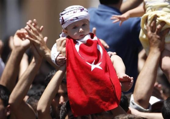 Người tị nạn Syria giơ cao đứa con nhỏ của mình trong cuộc biểu tình phản đối tổng thống Assad tại trại tị nạn ở Yayladagi, tỉnh Hatay, Thổ Nhĩ Kỳ ngày 1/7/2012.