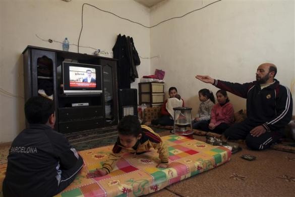 Người tị nạn Syria xem TV trong một căn nhà tạm thời của họ tại trại tị nạn Al Hussein ở Amman, Palestine ngày 10/1/2012.