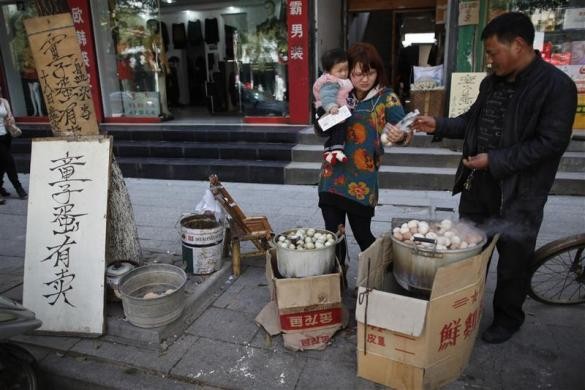 Ge Yaohua bán trứng luộc bằng nước tiểu bé trai cho một nữ khách hàng bế con nhỏ tại đường phố Dongyang ngày 26/3/2012