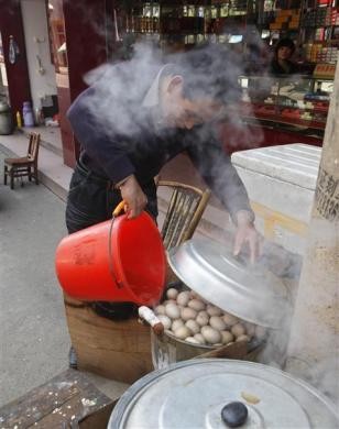 Một người bán trứng đổ xô nước tiểu vào nồi trứng luộc tại cửa hàng bán trứng của mình ở Dongyang ngày 26/3/2012