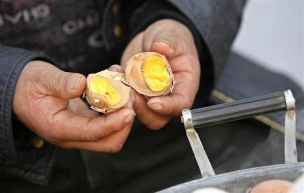 Ge Yaohua cho xem phần bên trong của quả trứng được luộc bằng nước tiểu của các bé trai tại Dongyang ngày 26/3/2012