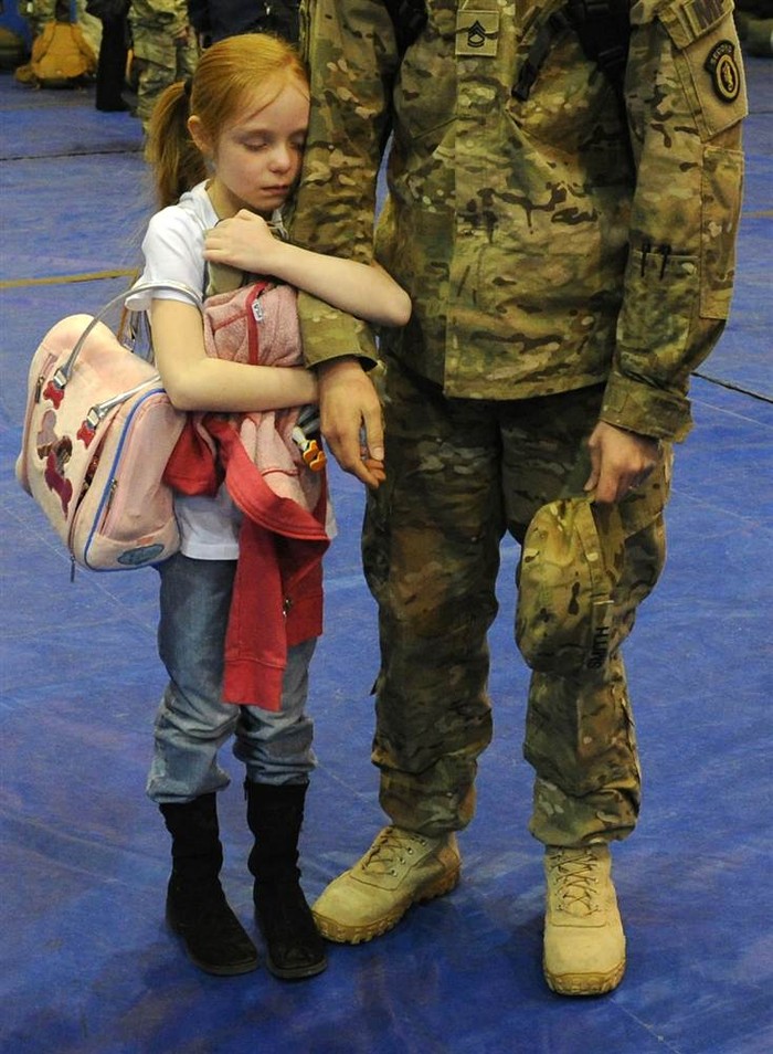 Cô bé Alyssa Smith ôm cánh tay của cha mình, Jonson Smith, khi anh trở về từ Afghanistan ngày 24/3 tại Anchorage, Alaska (Mỹ).