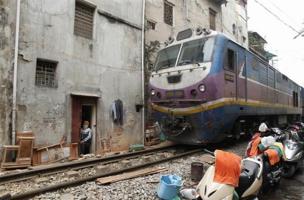 Người thợ mộc nghỉ tay khi đoàn tàu chạy qua cửa tại trung tâm thành phố Hà Nội ngày 27/12/2011