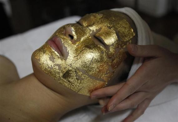 Một nhân viên đang đắp mặt nạ vàng lên mặt cho một khách hàng tại cửa hàng làm đẹp ở Hà Nội ngày 13/2/2012