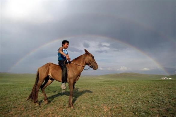 Trẻ em Mông Cổ cưỡi ngựa đi theo cầu vồng tại Khui Doloo Khudag, Ulan Bator ngày 10/7/2004.