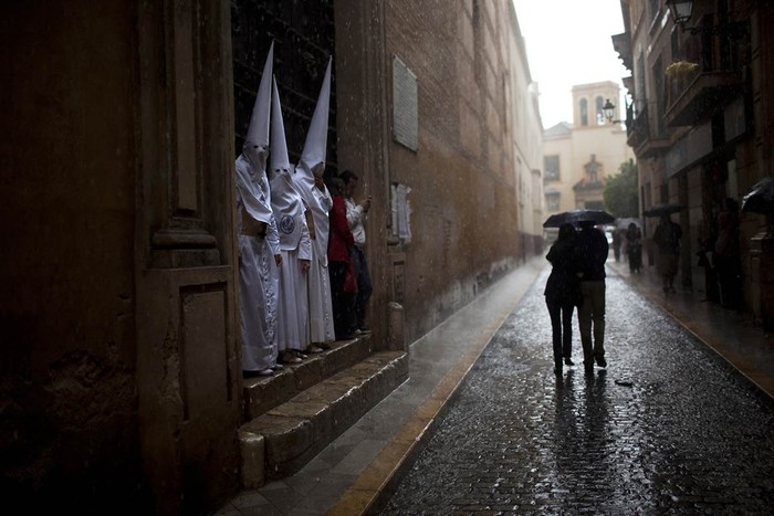 Các thành viên hội "La Candelaria" trú mưa bên dưới một tòa nhà ở Seville, Tây Ban Nha ngày 3/4. Hầu hết các lễ rước kiệu mừng lễ Phục sinh tại đây đã bị hủy bỏ do mưa bão.