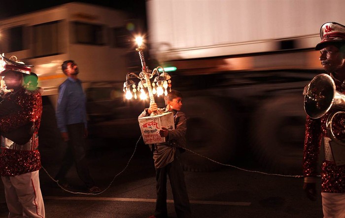 Cậu bé Ấn Độ bê chiếc đèn chờ đợi đám rước cô dâu bắt đầu tại Bijnor, Uttar Pradesh, Ấn Độ ngày 18/4.