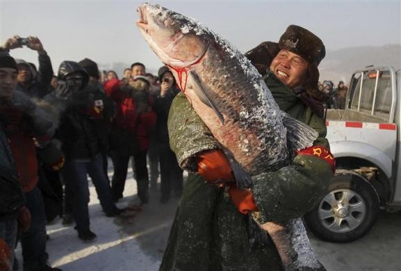 Người đàn ông hạnh phúc ôm con cá lớn nhất câu được trong ngày bắt đầu sự kiện đánh bắt cá mùa đông trên sông băng ở Trường Xuân, Cát Lâm, Trung Quốc ngày 25/1/2011.