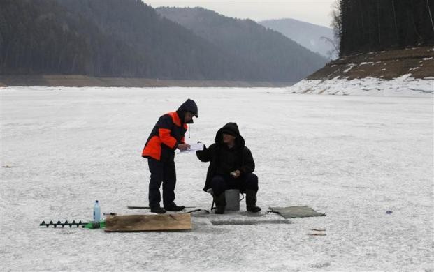Thành viên lực lượng cứu hộ khu vực giải thích các quy định về an toàn khi câu cá trên băng cho một người đàn ông trên sông Yenisei, cách phía nam thành phố Krasnoyarsk của Siberia, Nga khoảng 60 km ngày 20/4/2012.
