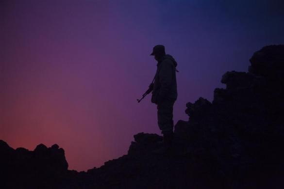 Một binh sĩ Congo bảo vệ công viên quốc gia Virunga được chiếu sáng trong chiều tối bởi ánh sáng từ một hồ dung nham sôi trong miệng núi lửa Nyiragongo gần Goma, miền đông Congo ngày 30/8/2010.