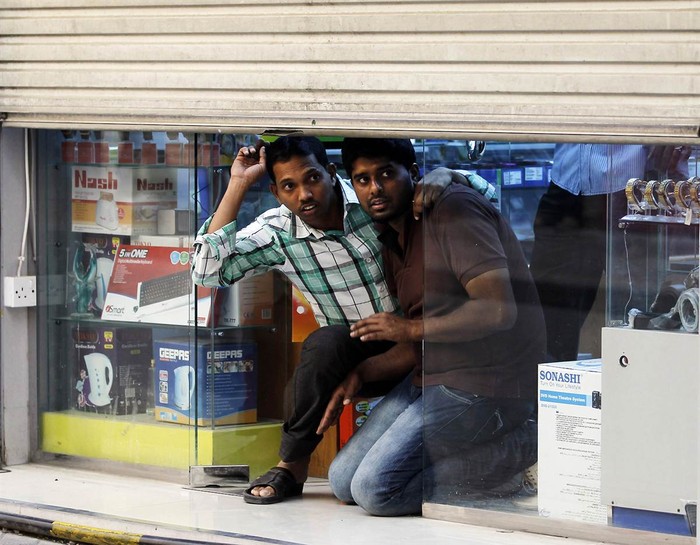 Chủ một cửa hàng nấp dưới khe cửa xem biểu tình chống chính phủ ở thủ đô Manama, Bahrain ngày 1/5