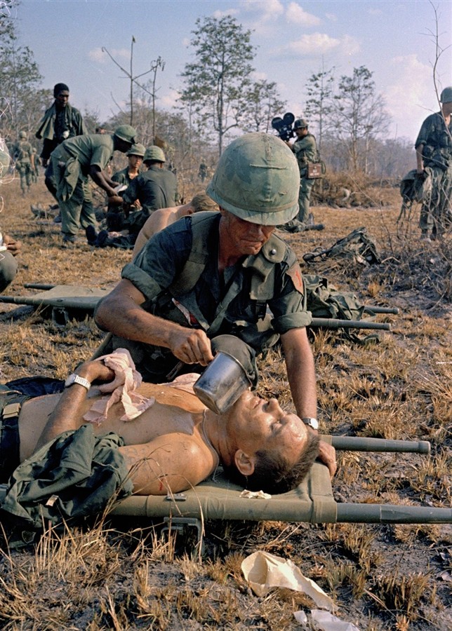 Một người lính Mỹ bị thương được đồng đội cho uống nước trên một chiến trường tại Việt Nam.