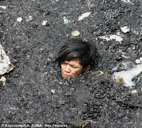 Người dân lội trong làn nước đầy tro và mảnh vụn ngập đến cổ cố cứu vớt tài sản sau đám cháy tại quận Tondo của Manila.