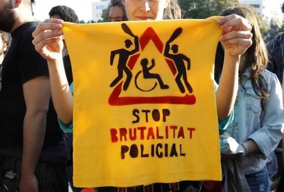 Người biểu tình giơ chiếc áo được phun dòng chữ "chấm dứt các hành động tàn bạo của cảnh sát" tại Barcelona ngày 14/5.