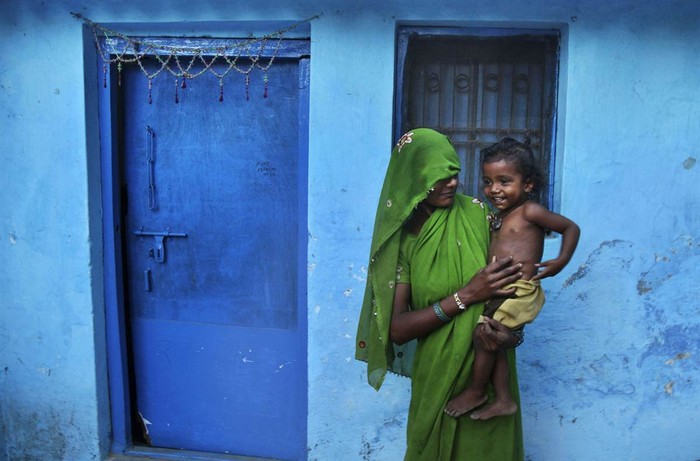 Một phụ nữ Ấn Độ bế con đứng trước cửa nhà của cô ở Allahabad, Ấn Độ ngày 13/5.