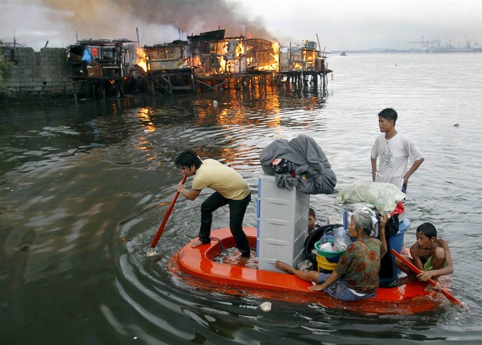 Người dân chèo thuyền nhằm thoát khỏi vụ hỏa hoạn đã thiêu rụi khu ổ chuột ở Manila, Philippines ngày 11/5.