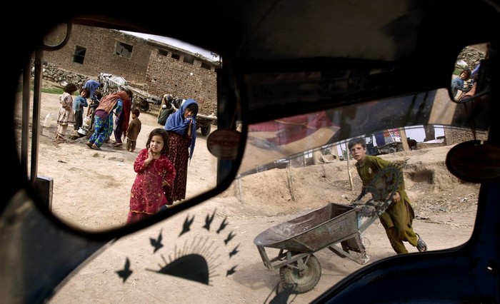 Bé gái Pakistan được nhìn thấy trên gương của chiếc xe tại khu ổ chuột ở ngoại ô Islamabad, Pakistan ngày 16/5.