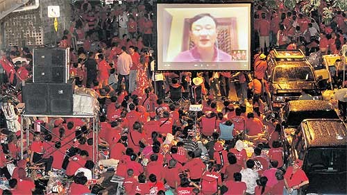 Người biểu tình lắng nghe bài phát biểu của ông Thaksin qua truyền hình vệ tinh. Ảnh Bangkok Post