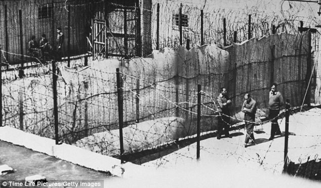 Eichmann đi dạo trong sân nhà tù dưới sự giám sát của hai lính gác.