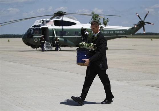 Một phụ tá của Tổng thống Obama bê chậu cây sồi (Emancipation Oak) còn non lên chiếc Marine One trên đường băng của căn cứ không quân Andrews ngày 9 tháng 5 năm 2010.
