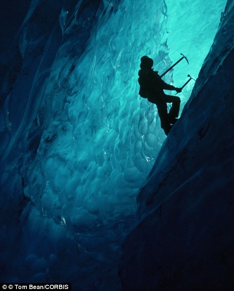 Một nhà leo núi đamg cố vượt qua một hang động băng bên dưới lòng dòng sông Muir.