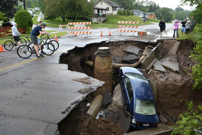 Một chiếc xe bị lao xuống hố được tạo ra bởi nước lũ tại Duluth, Minnesota, Mỹ ngày 20/6.