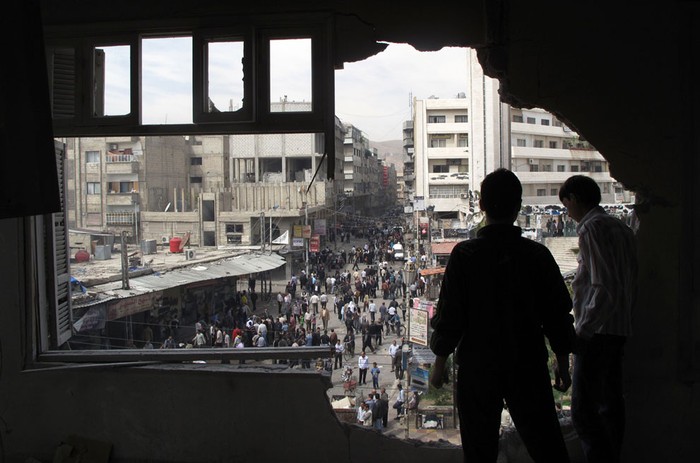 Các bé trai Syria đứng trong một tòa nhà bị phá hủy bởi đạn pháo tại Damascus ngày 6/4/2012.