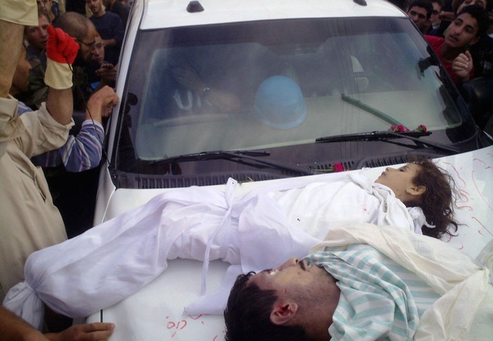 Thi thể của một người đàn ông và trẻ em mà những người biểu tình nói rằng họ đã bị giết bởi lực lượng an ninh chính phủ được đặt trên một chiếc xe của các nhà quan sát Liên hợp quốc tại Houla, Syria ngày 26 tháng 5 năm 2012.