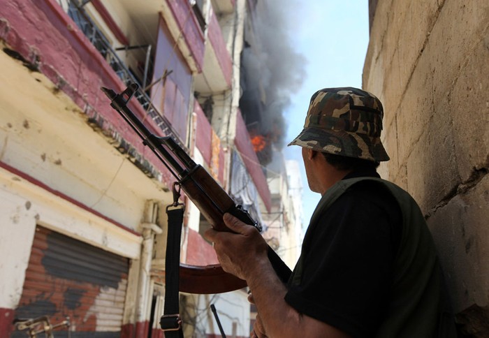 Một tay súng Sunni đứng gần tòa nhà đang bốc cháy trong một cuộc đụng độ nổ ra tại thành phố cảng phía bắc Tripoli, Lebanon ngày 2 tháng 6 năm 2012. Các cuộc đụng độ giữa những nhóm ủng hộ và phản đối cuộc biểu tình tại Syria ở Lebanon đã giết chết 1 người và làm bị thương ít nhất 9 người khác.