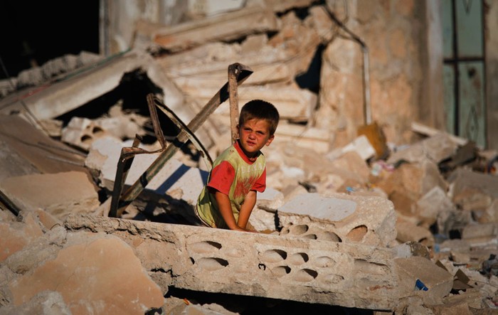 Một cậu bé Syria nằm trong đống đổ nát của ngôi nhà đã bị phá hủy do một hoạt động quân sự được lực lượng ủng hộ tổng thống Syria tiến hành vào tháng 4 năm 2012, ở thị trấn Taftanaz, cách phía đông Idleb 15 km.
