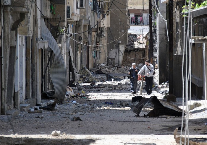 Người Syria bước đi trong một con hẻm bị phá hủy bởi pháo kích tại Bab Sbaa, tỉnh Homs ngày 21/4/2012.