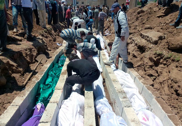 Người dân tụ tập tại một ngôi mộ tập thể dành cho các nạn nhân được cho là đã bị thiệt mạng trong một cuộc pháo kích của lực lượng chính phủ tại Houla ngày 26 tháng 5 năm 2012.