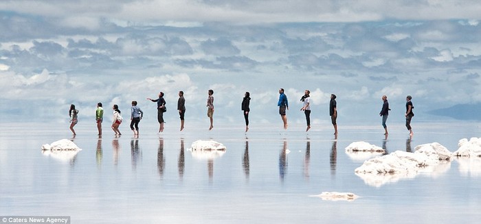 Khách du lịch thích thú tận hưởng khả năng phản xạ tuyệt vời của hồ muối Salar de Uyuni, Bolivia.