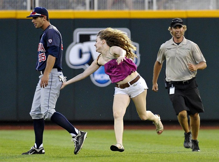 Một nữ cổ động viên táo bạo chạy xuống sân vỗ vào người cầu thủ Joey Rickard trong chung kết bóng chày tại nam Carolina, Omaha, Nebraska, Mỹ ngày 25/6.