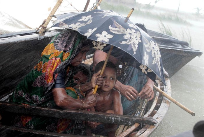 Một bà mẹ cố gắng che mưa cho đứa con trai nhỏ trên chiếc thuyền chạy lụt tại ngôi làng đã bị chìm trong nước ở Kurigram, Bangladesh ngày 3/7. Hơn 100 người đã thiệt mạng và hàng trăm ngàn người khác buộc phải di tản do mưa lớn gây lụt trên khắp đất nước Bangladesh.