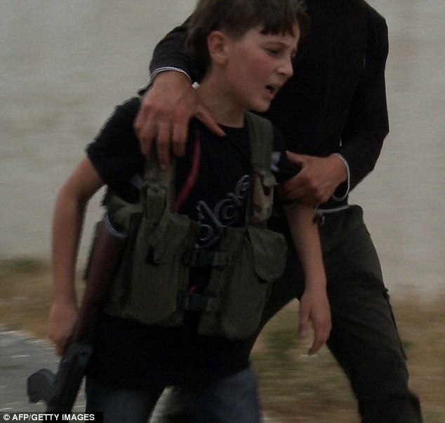 Một cậu lính nhỏ Syria được một tay súng an ủi sau khi bạn cậu bé thiệt mạng trong một trận chiến chống lại lực lượng an ninh chính phủ ở ngoại ô Homs.