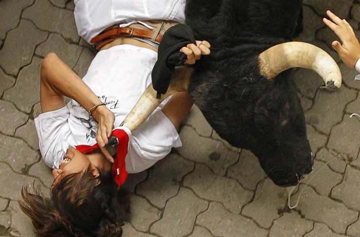 Một người đàn ông vật lộn với con bò tót tại lễ hội San Fermin ở Pamplona, Tây Ban Nha ngày 7/7.