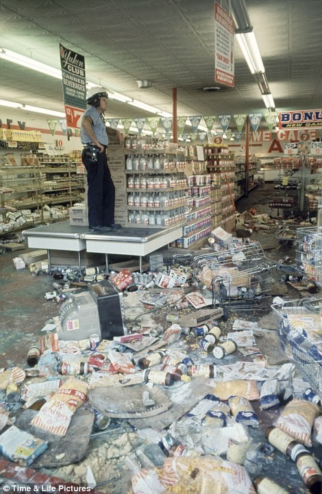 Một sĩ quan cảnh sát Detriot đứng bên trong một cửa hàng bị cướp phá trong cuộc bạo loạn.
