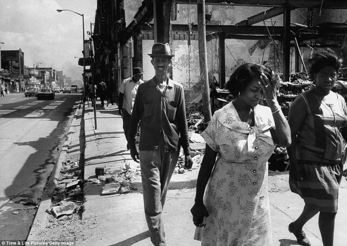 Một gia đình người Mỹ gốc Phi đi bộ trên khu phố bị phá hủy bởi các cuộc đụng độ giữa người da màu và lực lượng cảnh sát.