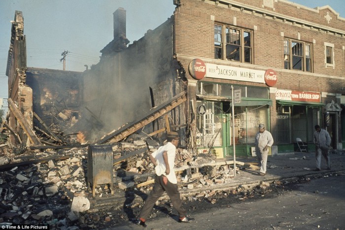 Người dân đi ngang qua một tòa nhà đổ nát và bị thiêu hủy trong cuộc bạo loạn sắc tộc tại Detriot, bang Michigan, Mỹ năm 1967.