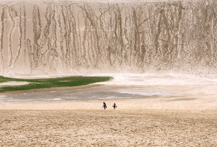 Hai đứa trẻ đi bộ trên những đụn cát ở Tottori, Nhật Bản ngày 21/7. Những đụn cát này trải dài trên diện tích lên khoảng 19km2, tồn tại hơn 100.000 năm qua nhưng đang được thu hẹp lại nhờ một chương trình trồng rừng của chính phủ sau chiến tranh thế giới thứ 2.