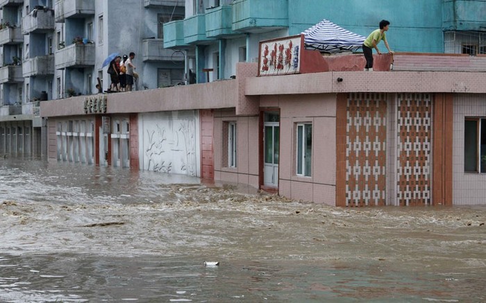 Người dân chờ đợi được giải cứu trên mái của một tòa nhà bị ngập nước trong thành phố Anju.