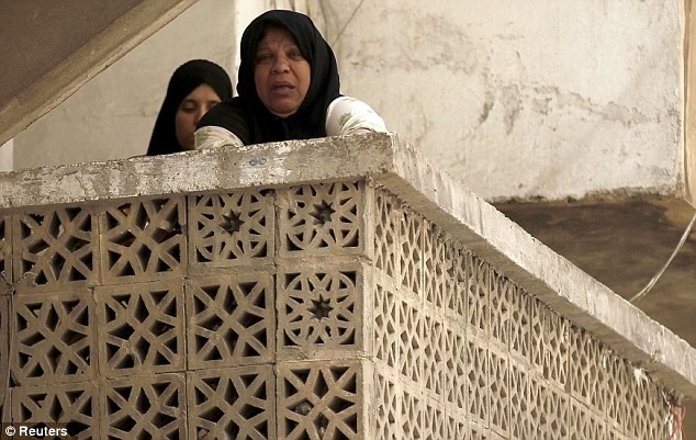 Hai người phụ nữ trốn trên ban-công khi nghe tiếng pháo kích ở Aleppo.