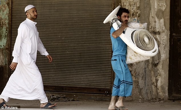 Một người đàn ông Syria mang theo gối và quạt khi rời bỏ thành phố Aleppo.