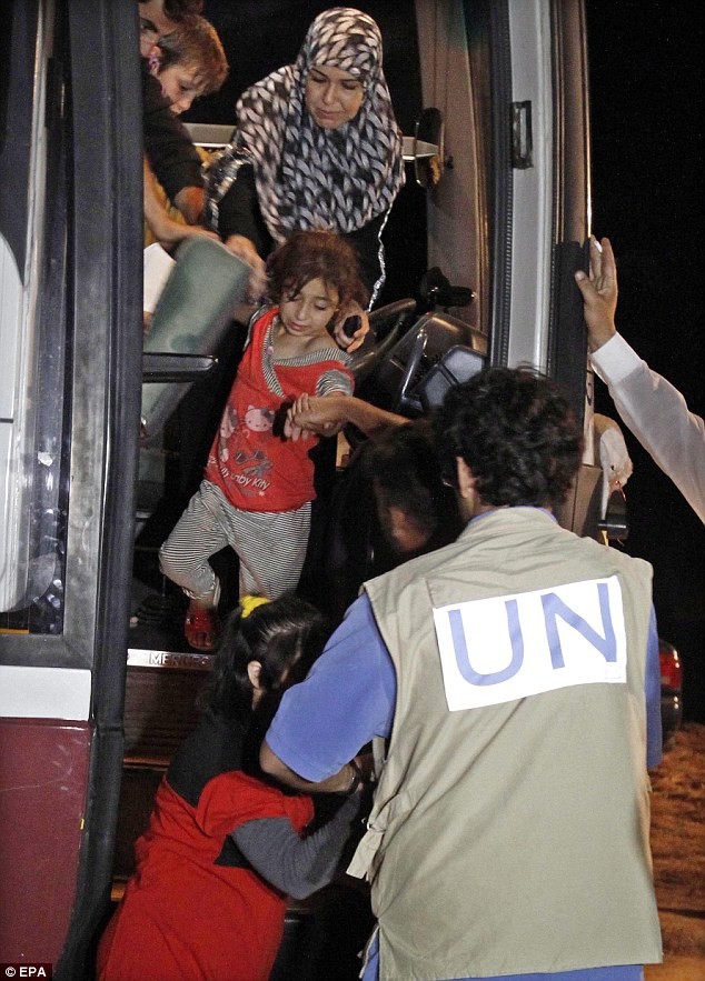 Một nhân viên Liên Hợp Quốc giúp những người Syria xuống xe sau khi họ được đưa tới một trại tị nạn ở Jordan.