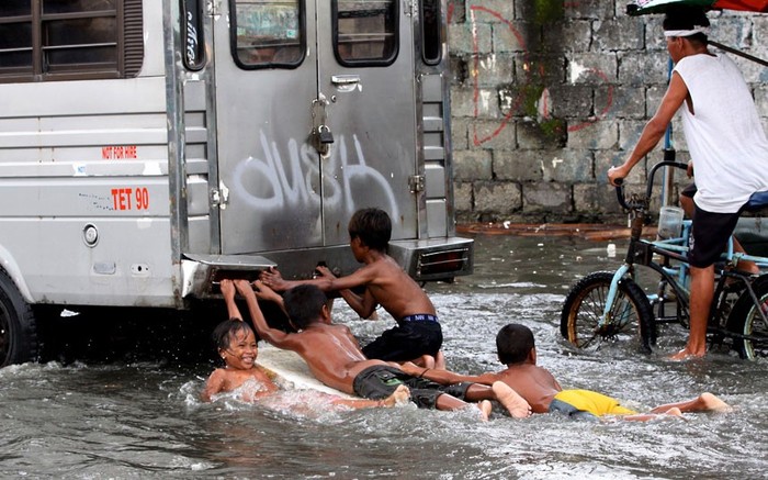 Trẻ em bám vào đuôi chiếc xe tải trên đường phố ở thành phố Navotas, phía bắc Manila.