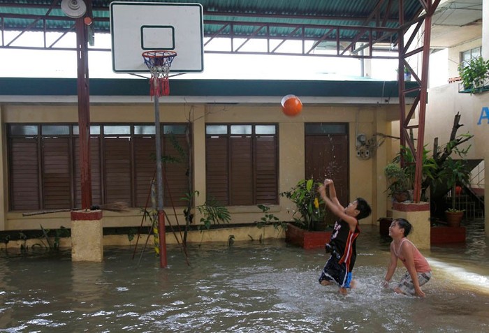 Chơi bóng rổ trong sân trường ngập nước tại thị xã Almacen, tỉnh Bataan, phía bắc Manila.