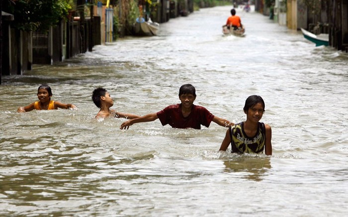 Trẻ em di chuyển trên đường phố ngập nước ở Almacen, tỉnh Bataan, phía bắc Manila.